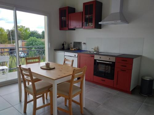 une cuisine avec des placards rouges et une table avec des chaises dans l'établissement Gîtes Mer, à Saint-Laurent-de-Médoc