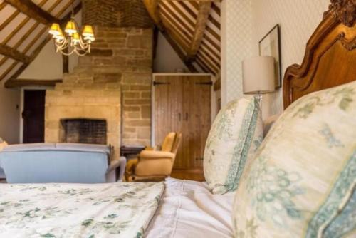 Pinley Hill House في هاتون: غرفة نوم مع سرير ومدفأة حجرية