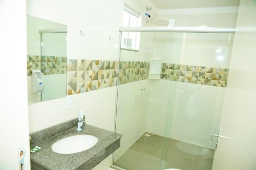 ein weißes Badezimmer mit einem Waschbecken und einem Spiegel in der Unterkunft London Executive Hotel in Cafelândia