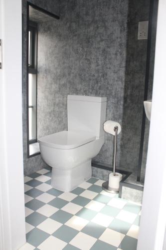 a white toilet in a bathroom with a checkered floor at The Royal Hotel and Bar in Lancaster