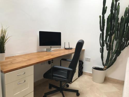 a desk with a computer and a chair and a cactus at The Coach House in Cardiff