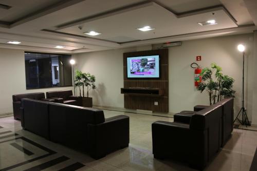 a waiting room with leather chairs and a flat screen tv at Ouro Minas Plaza Hotel in Aparecida