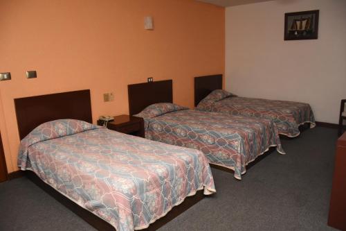 a hotel room with two beds and orange walls at Hotel Maria Victoria Xalapa in Xalapa