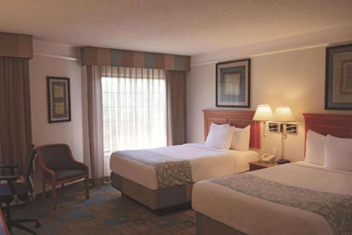 a hotel room with two beds and a chair at La Quinta Inn by Wyndham Austin Oltorf in Austin