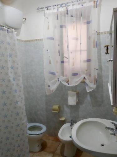 a bathroom with a toilet and a sink and a shower curtain at casa Ada in SantʼAntìoco