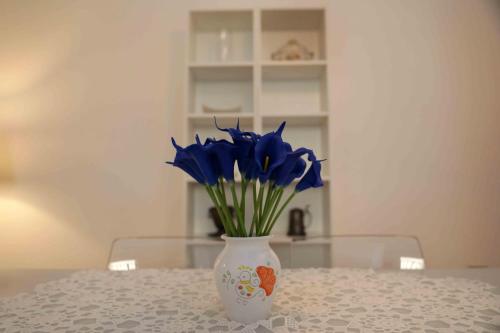 a white vase with blue flowers in it on a table at casa Ada in SantʼAntìoco
