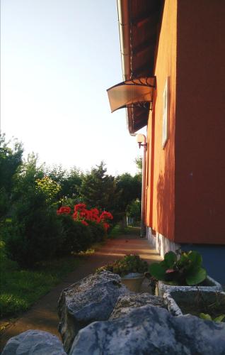 a building with rocks in front of a building with red flowers at Kuća za odmor Mirni kutak Vukovar in Vukovar
