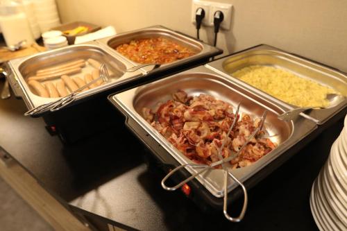 a buffet with three trays of food on a table at Lignum Hotel in Miskolctapolca