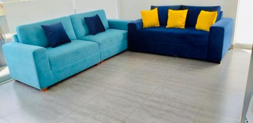 two blue couches with yellow pillows in a living room at Las palmeras de bocapan in Tumbes