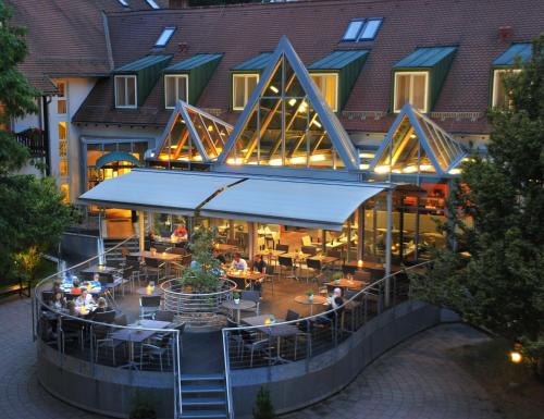 an outdoor restaurant with people sitting at tables in front of a building at Landhotel Burg im Spreewald - Resort & Spa in Burg