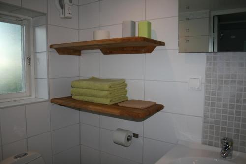 Baño con toallas en un estante sobre un fregadero en Lilla Huset på Slätten B&B en Lund