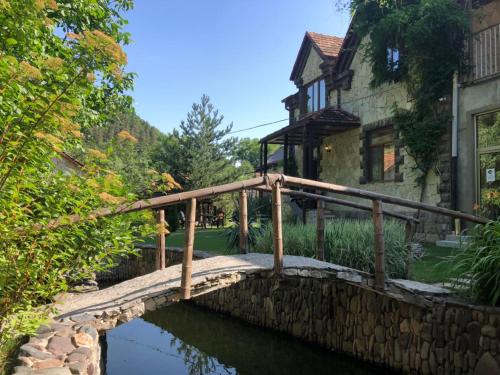 a wooden bridge over a pond in front of a house at ECO GARDEN in Dilijan