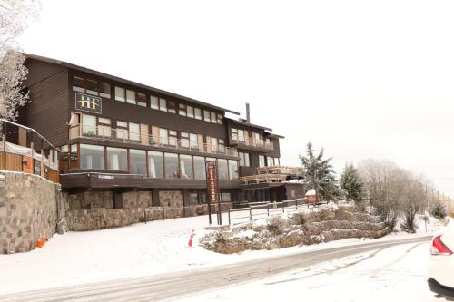 a large building on a snowy street with a car parked in front at Hotel HF in Farellones