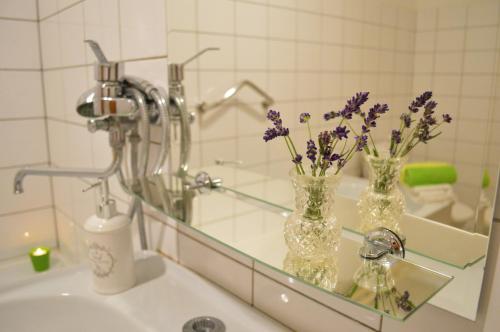 a bathroom with two vases with purple flowers on a sink at Apartmány LÍVIA Litmanová in Litmanová