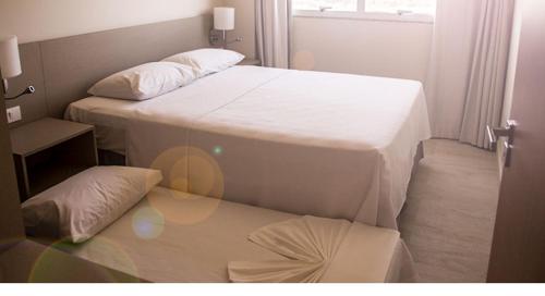 zwei Betten in einem kleinen Zimmer mit Fenster in der Unterkunft Salinas Park Resort in Salinópolis