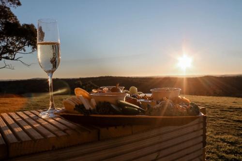 a table with a plate of food and a glass of wine at Rosewood Farmstay in Binda