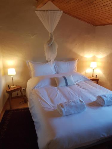 a white bed with two pillows and two lamps at Abrigo Montesinho in Montezinho