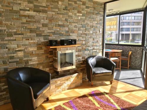 a living room with two chairs and a fireplace at Departamento en Playa Acapulco viña del mar in Viña del Mar