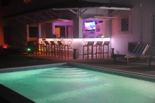 a swimming pool at night with chairs and a bar at Residence Helios in Abidjan