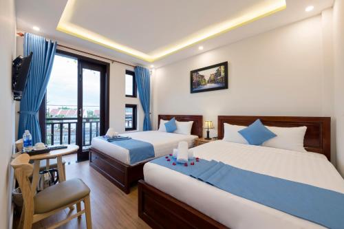 um quarto de hotel com duas camas e uma varanda em Hoi An Impression Homestay em Hoi An