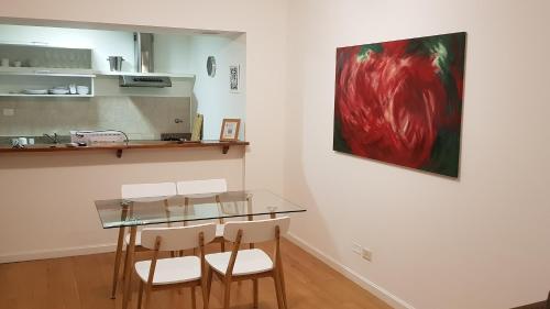 a dining room with a glass table and white chairs at Encantador departamento con cochera cubierta - By BUMEN in Vicente López