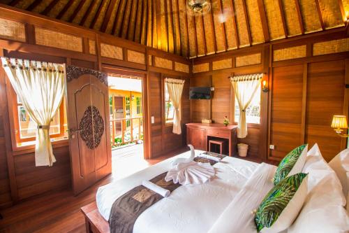 1 dormitorio con 1 cama grande en una habitación con paredes de madera en Villa Waturenggong Ubud, en Ubud