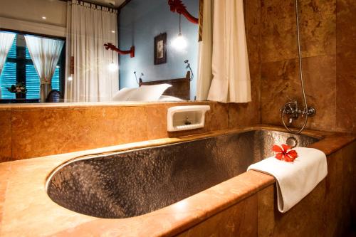 a bathroom with a large bath tub with a towel at Hotel Tugu Malang - CHSE Certified in Malang