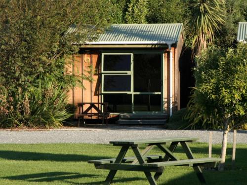 a picnic table in front of a cabin at Alpine-Pacific Holiday Park in Kaikoura