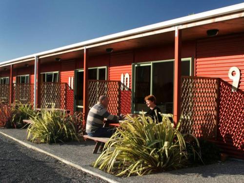 a man and woman sitting in front of a building at Alpine-Pacific Holiday Park in Kaikoura