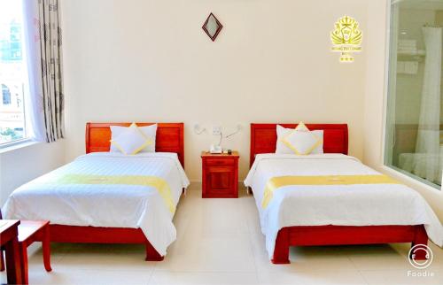 two beds in a room with white walls at Hoang Yen Canary Hotel in Quy Nhon
