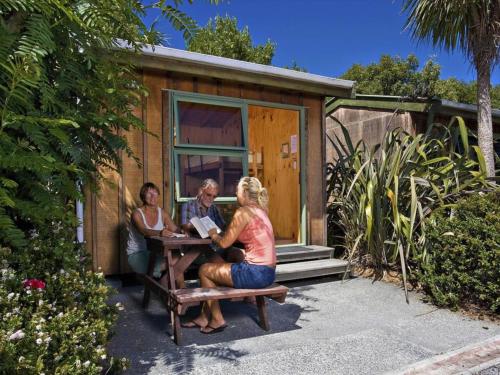 three women sitting at a table outside of a tiny house at Alpine-Pacific Holiday Park in Kaikoura