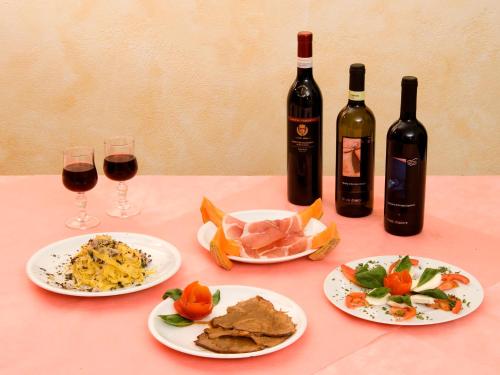 a table with two glasses of wine and plates of food at Hotel Belvedere in Castrocaro Terme