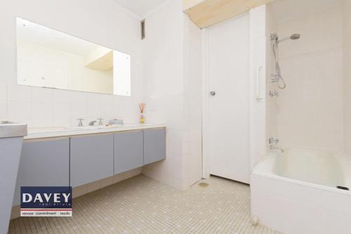 a white bathroom with a tub and a sink at Apartment with a View in Perth