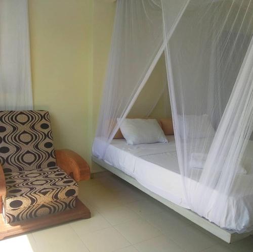 a bedroom with a bed with curtains and a chair at Secret Garden Galle Fort in Galle