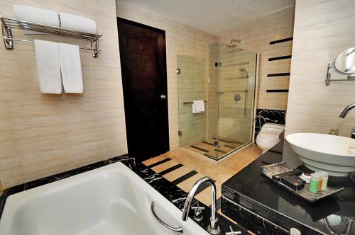 
a bathroom with a tub, toilet and sink at Gumaya Tower Hotel in Semarang
