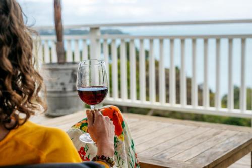 a woman holding up a glass of red wine at The Settlers Hut in Oneroa