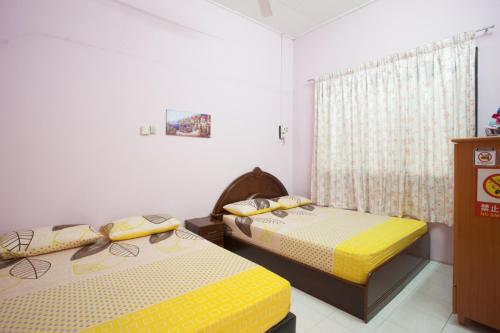 a bedroom with two beds and a window at Homestay Chin Ipoh in Ipoh