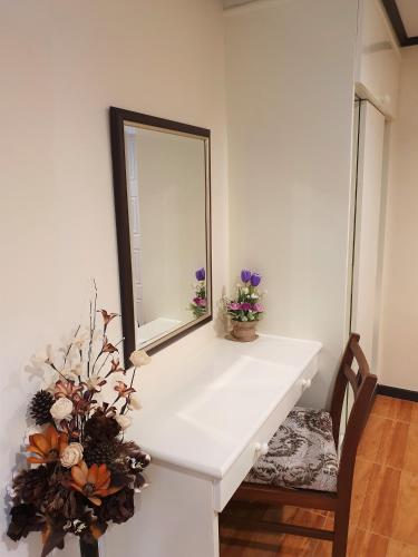 a mirror on a white counter with a chair and flowers at Cana Boutique Hotel in Bangkok