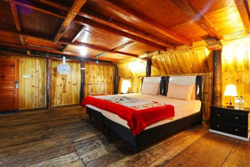 a bedroom with a bed in a room with wooden walls at Tuk Tuk Timbul Bungalows in Tuk Tuk