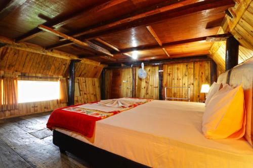 Cama grande en habitación con paredes de madera en Tuk Tuk Timbul Bungalows, en Tuk Tuk