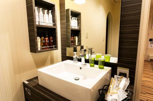 La salle de bains est pourvue d'un lavabo blanc et d'un miroir. dans l'établissement Hotel WILL Kashiwa (Adult Only), à Kashiwa