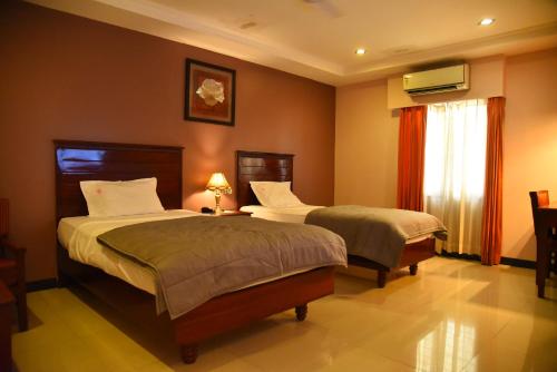 a bedroom with two beds and a window at Hotel Subhalakshmi Palace in Kāraikkudi