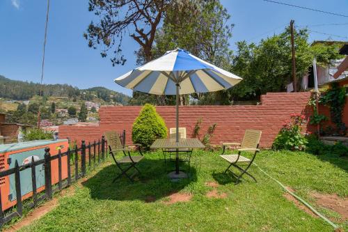 a table and chairs with an umbrella in the grass at FabExpress Wenlock Homes in Ooty