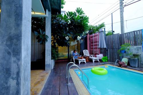 a man sitting in a chair next to a swimming pool at ลอฟท์แอทสีมา สาขา2 in Nakhon Ratchasima