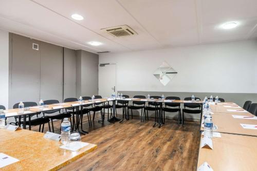 a conference room with tables and chairs in front of a screen at Comfort Hotel Grenoble Meylan in Meylan