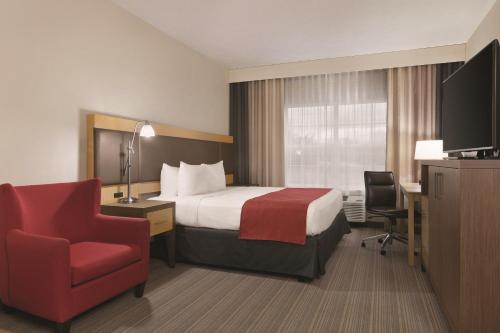 a hotel room with a bed and a red chair at Country Inn & Suites by Radisson, Fairborn South, OH in Fairborn