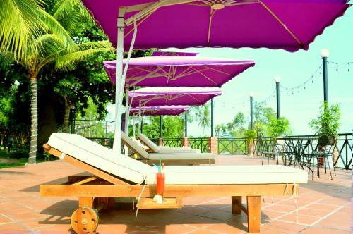a group of purple umbrellas sitting on a patio at Con Khuong Resort Can Tho in Can Tho