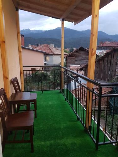 a balcony with green flooring and chairs and a view at Yana Guest House in Dobrinishte