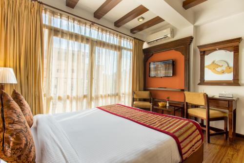a bedroom with a bed and a desk and a window at Hotel Moonlight in Kathmandu