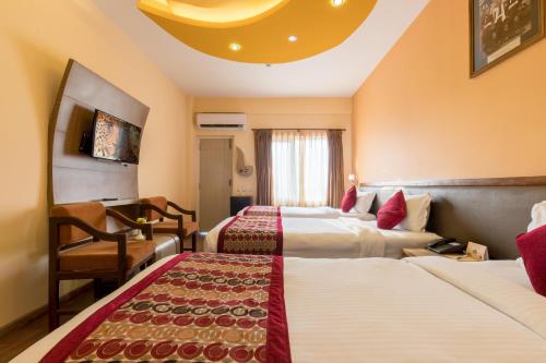 a hotel room with two beds and a chair at Hotel Moonlight in Kathmandu